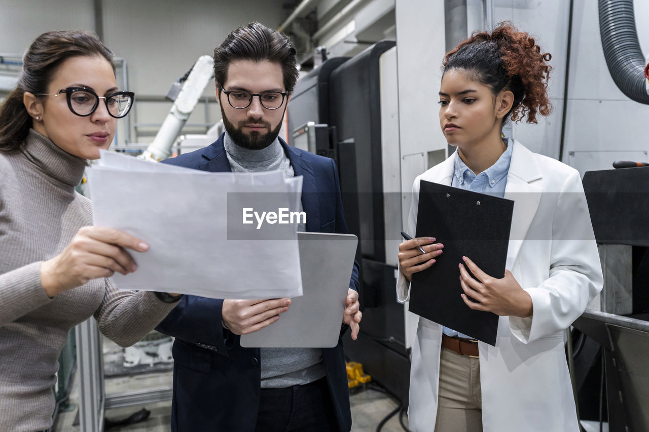 Businesswoman discussing over document with colleagues in industry