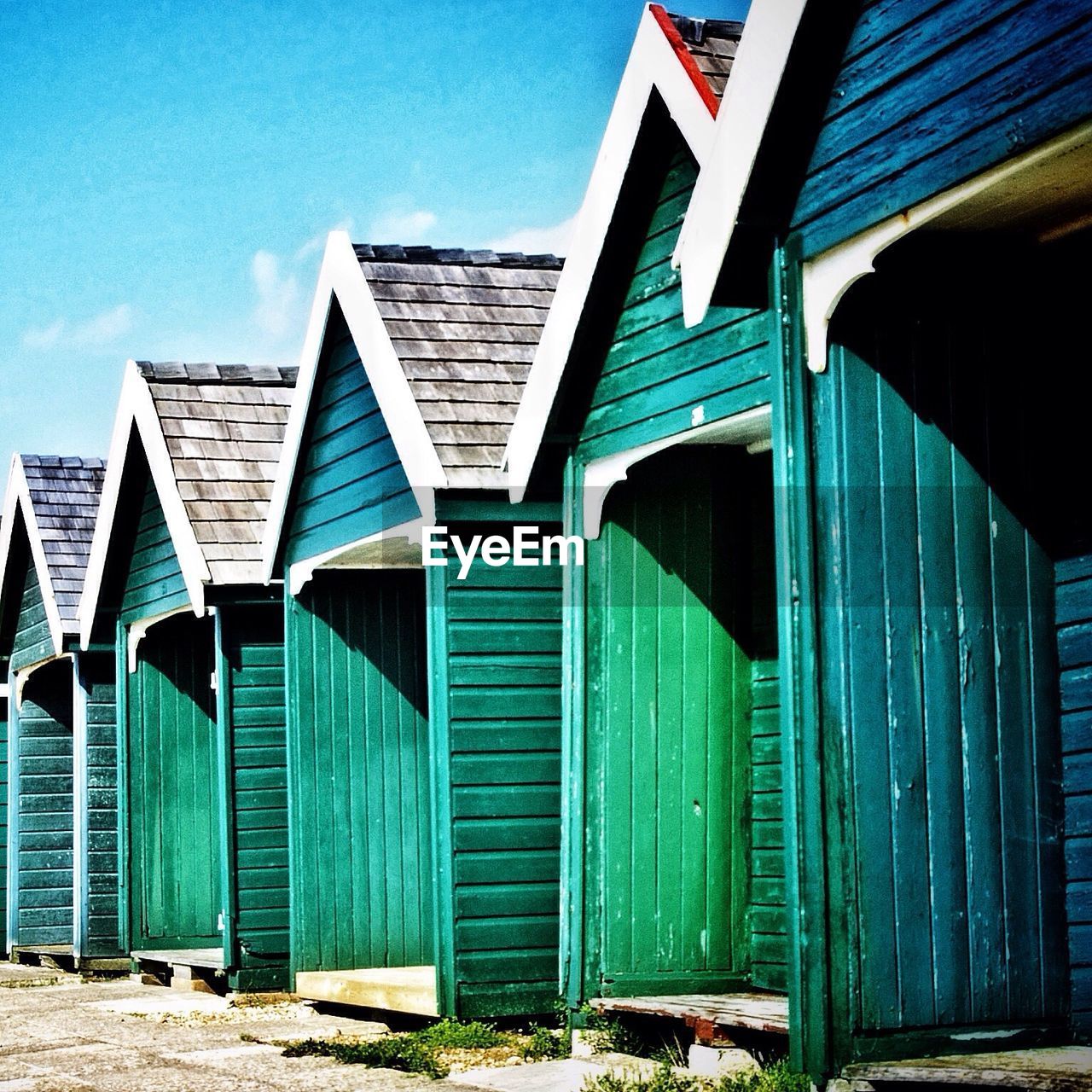 Row of green beach huts against sky