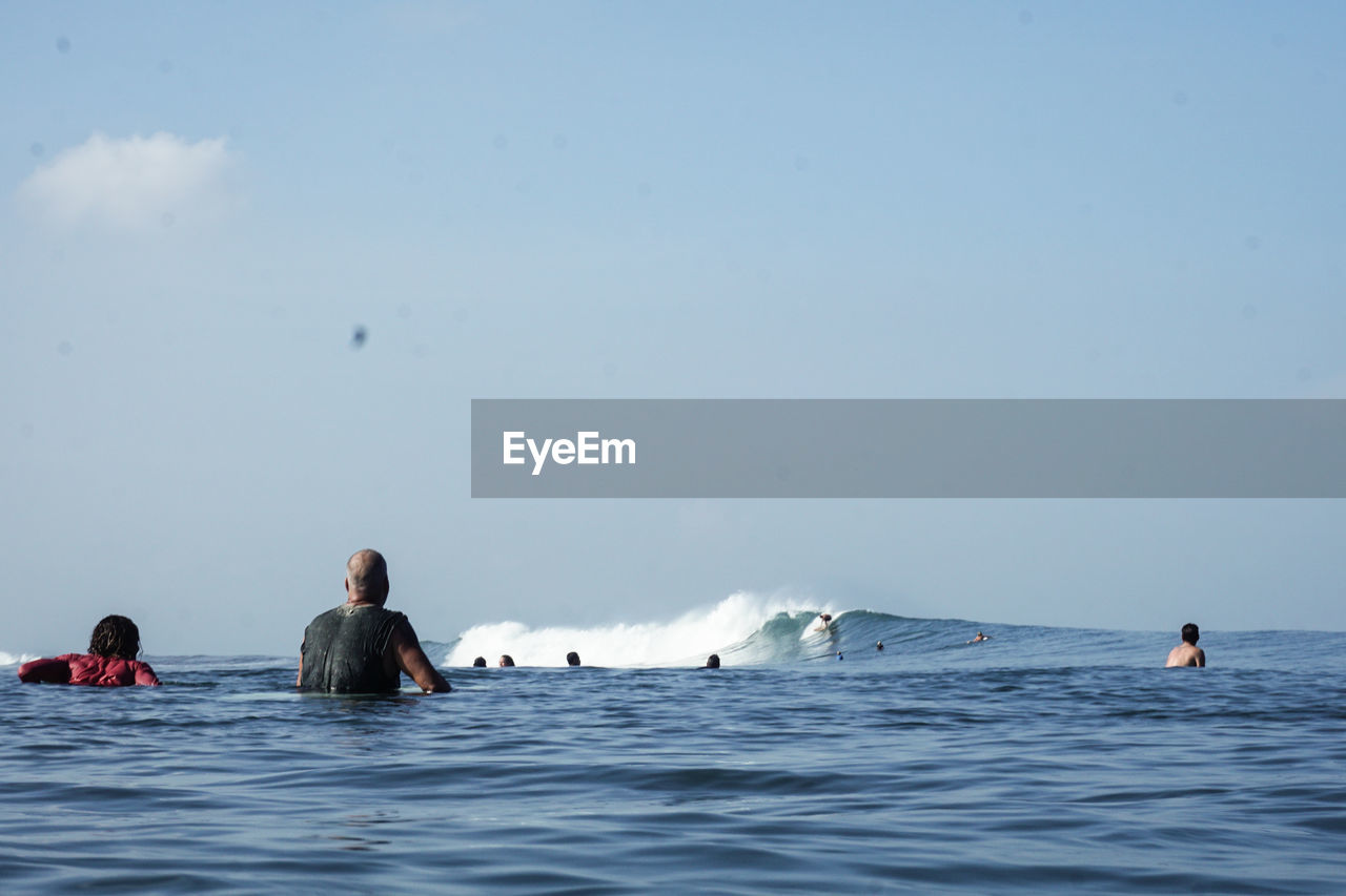 People surfing in  bali against sky