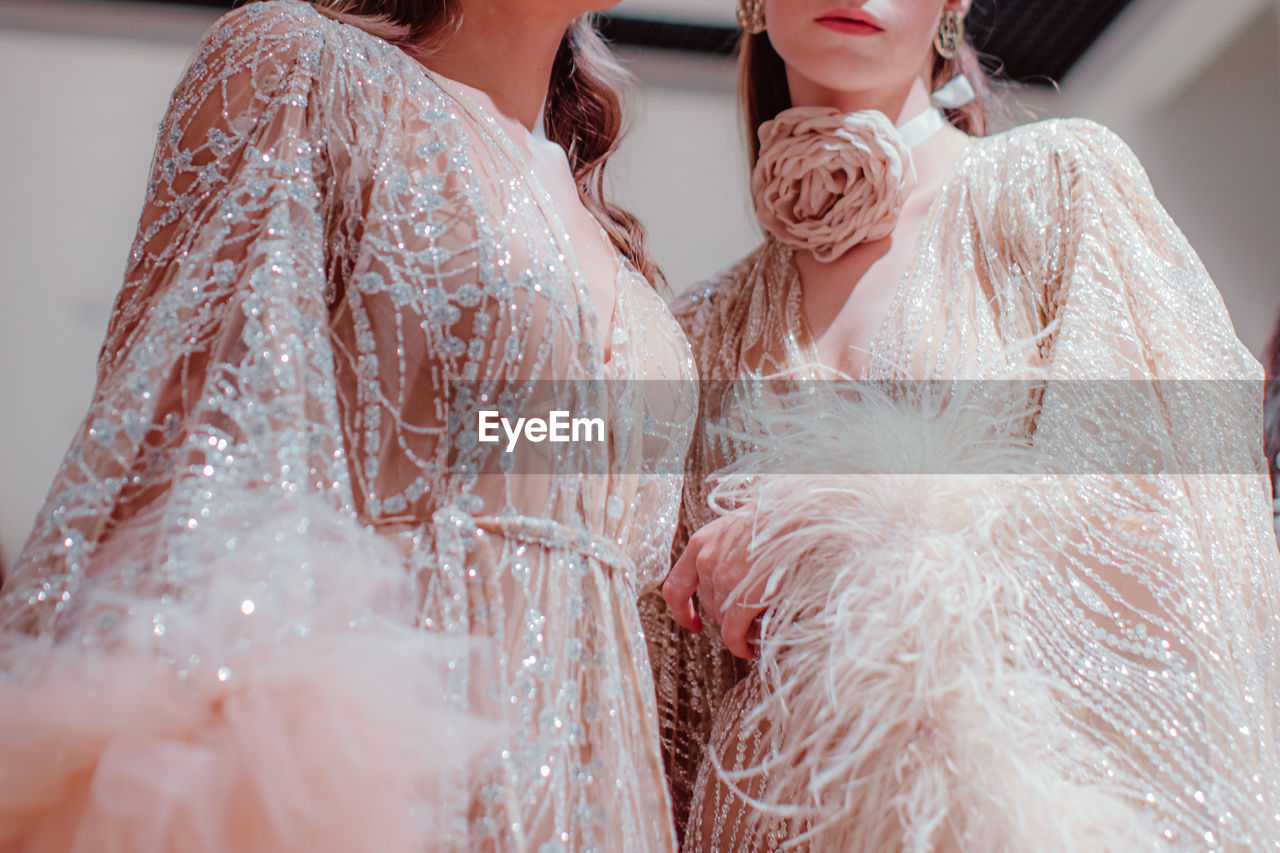 Elegant details of pastel pink haute couture boudoir dresses and a rose accessory around the neck