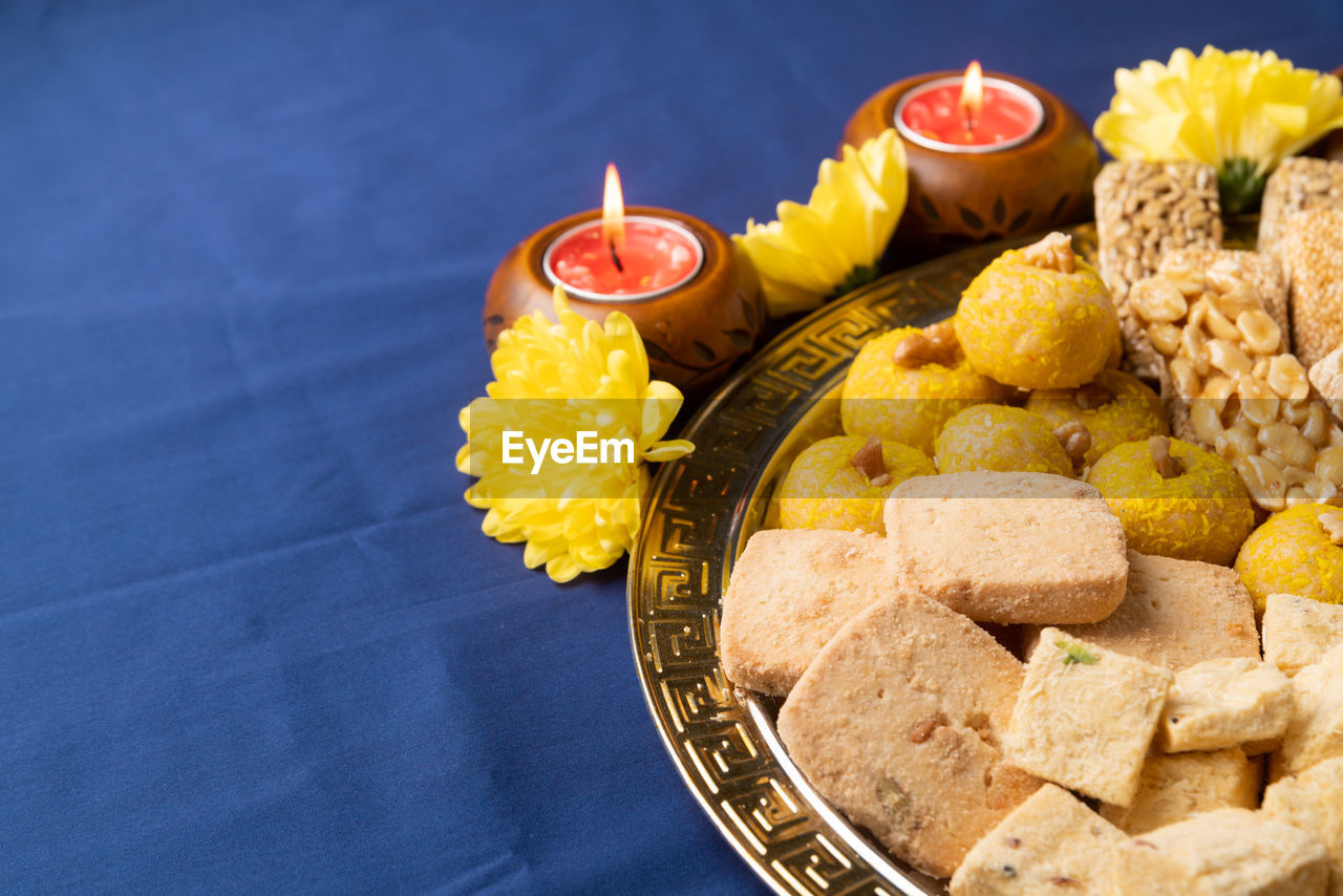 Indian traditional sweets laddu, soan papdi, burfi for festival on blue background with copy space