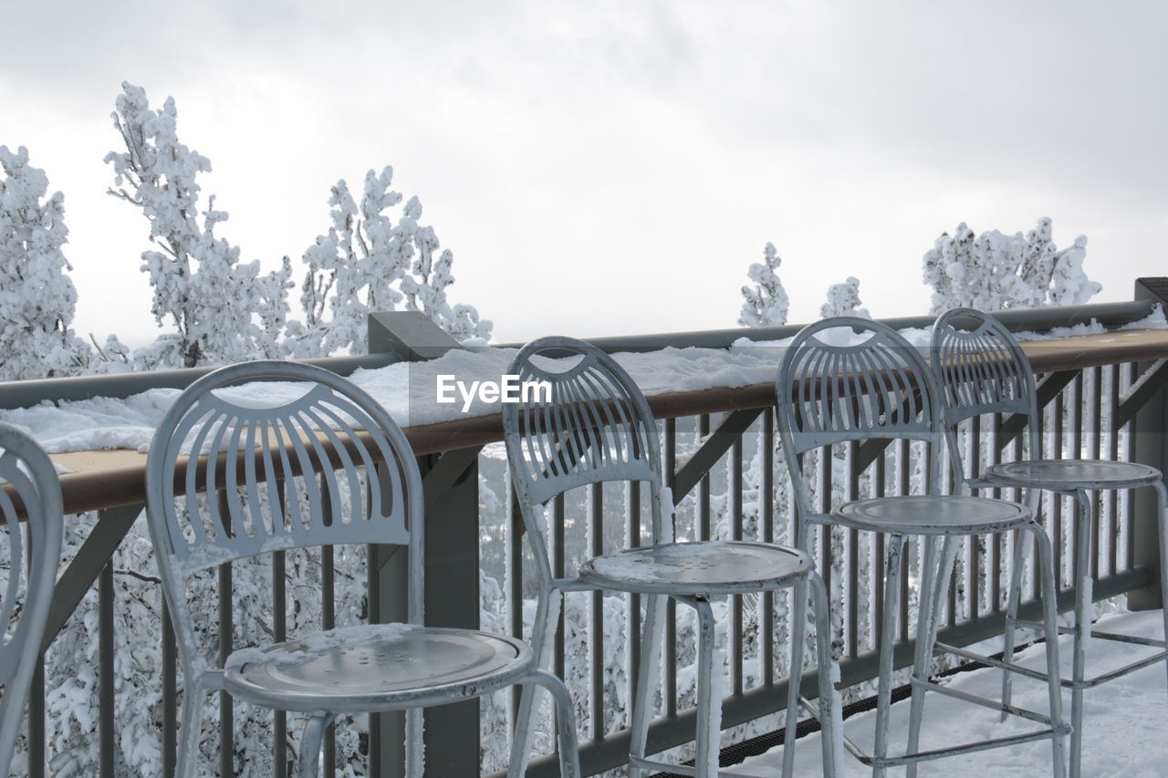 CLOSE-UP OF EMPTY CHAIRS AND TABLES AGAINST SKY