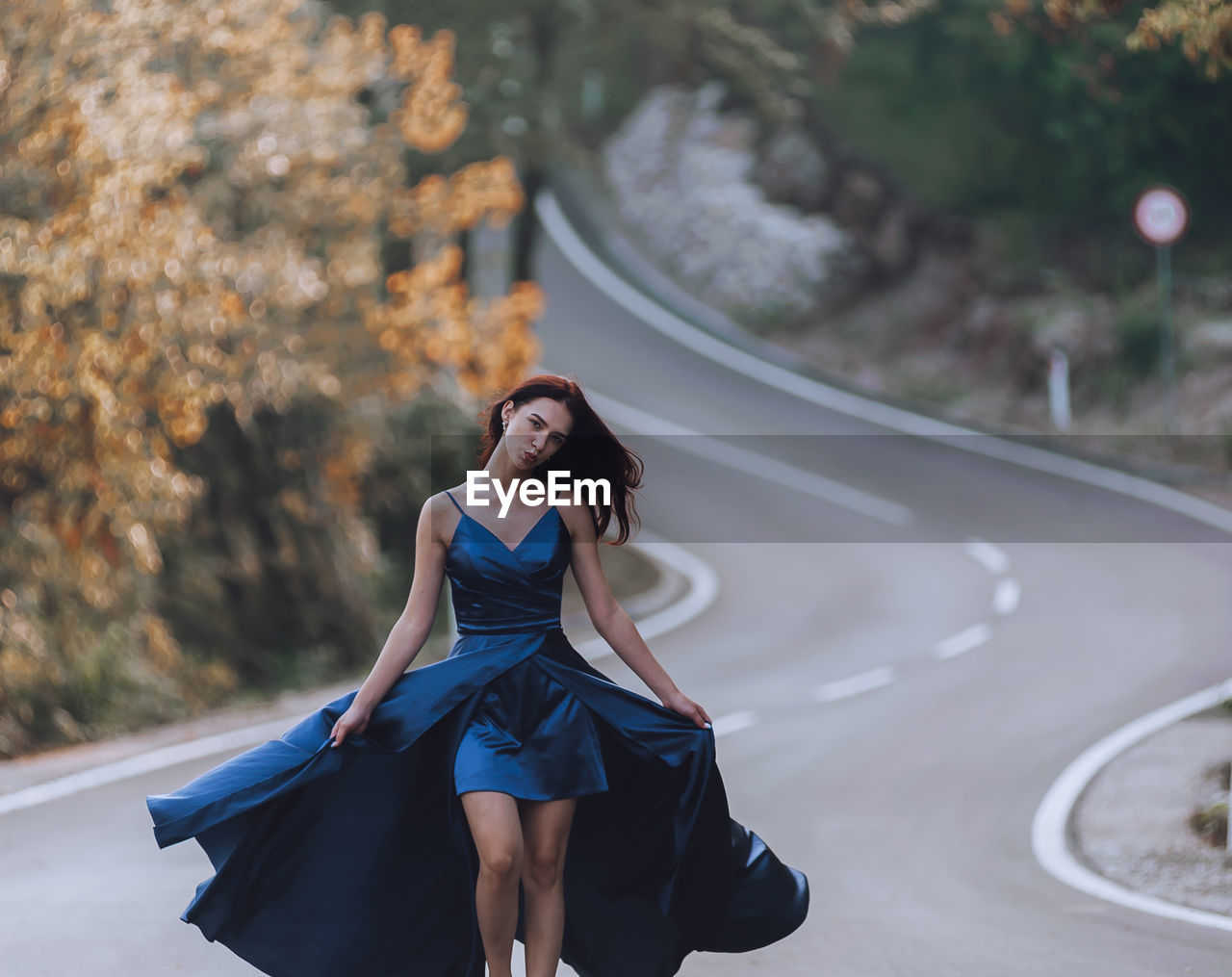 Young woman in blue dress walking on the road
