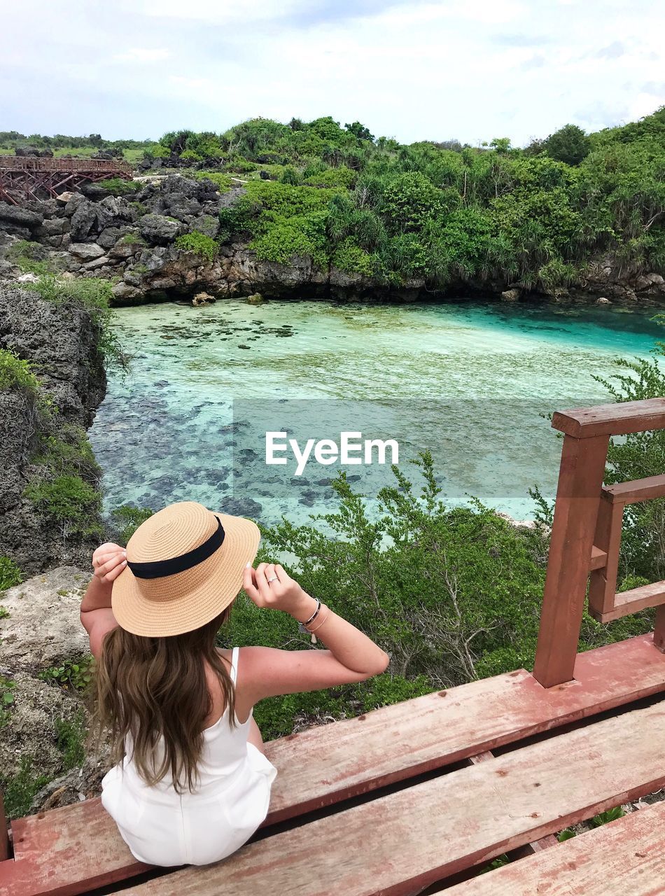 High angle view of woman sitting on pier over lake