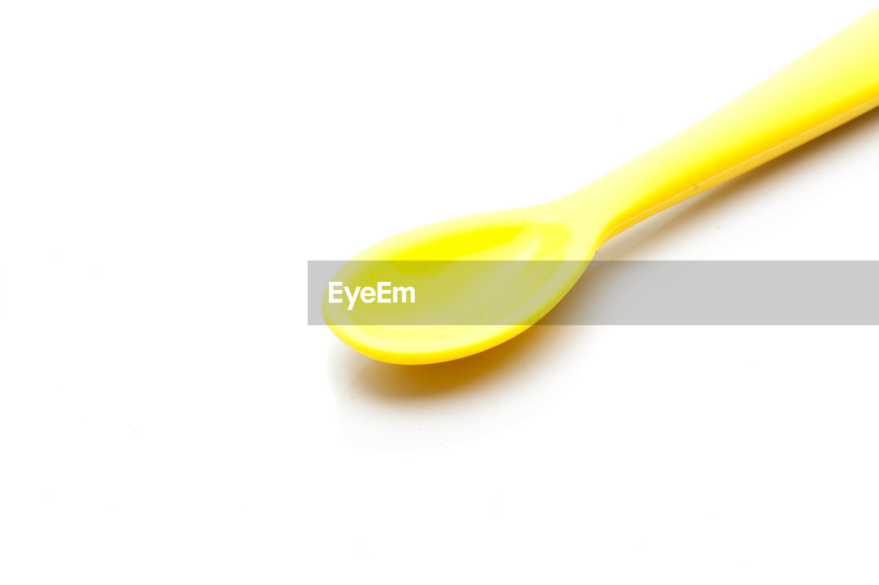 Close-up of yellow spoon against white background