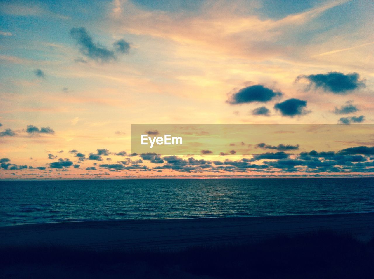 SCENIC VIEW OF BEACH AGAINST SKY DURING SUNSET