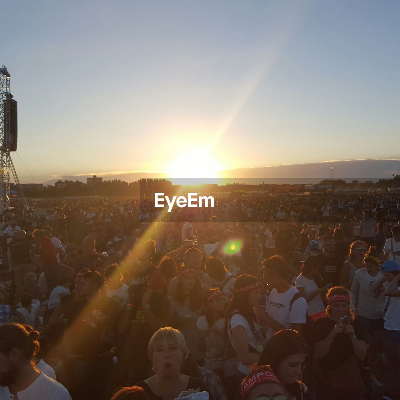 Crowd at music concert against sky during sunset