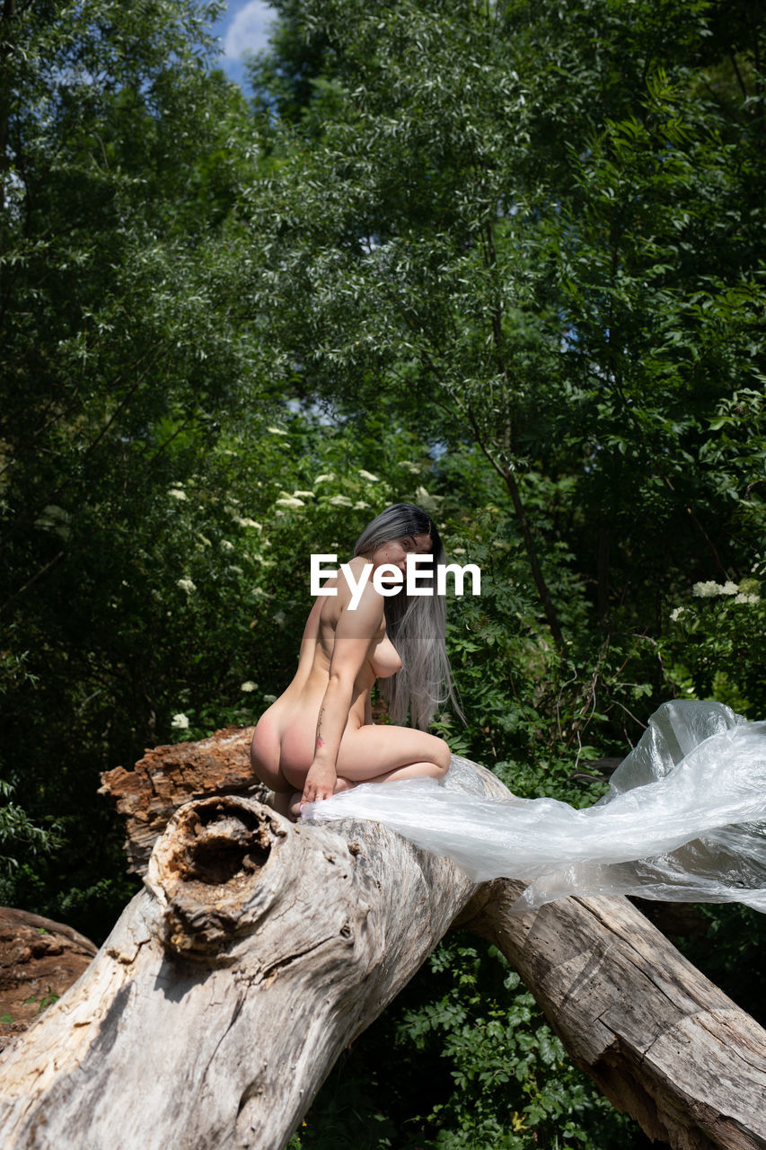 Woman sitting on wood in forest