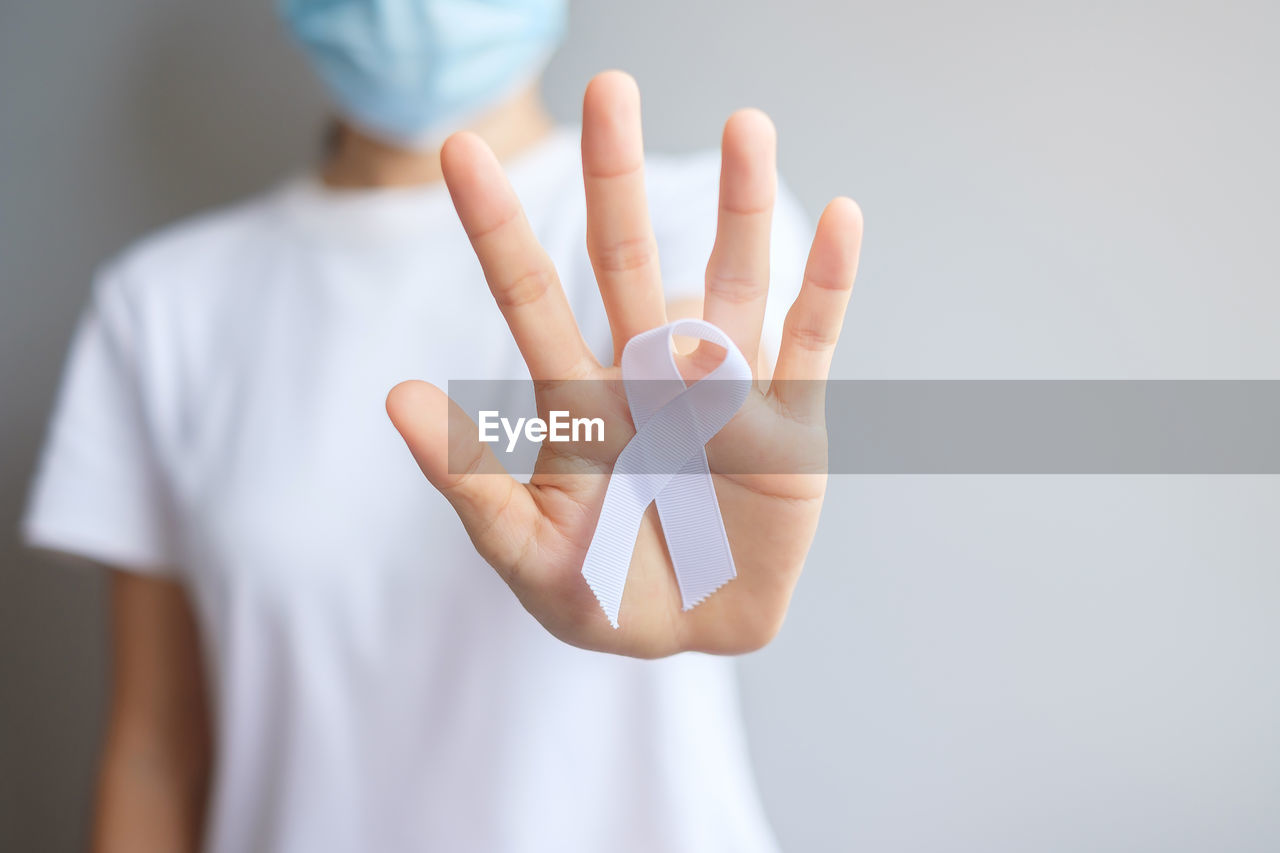 midsection of doctor holding human hand against white background