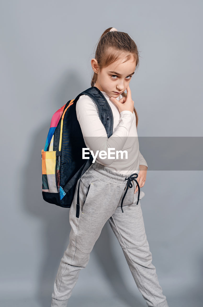 Little girl with backpack. schoolgirl with backpack looks seriously and frowning. problems at school