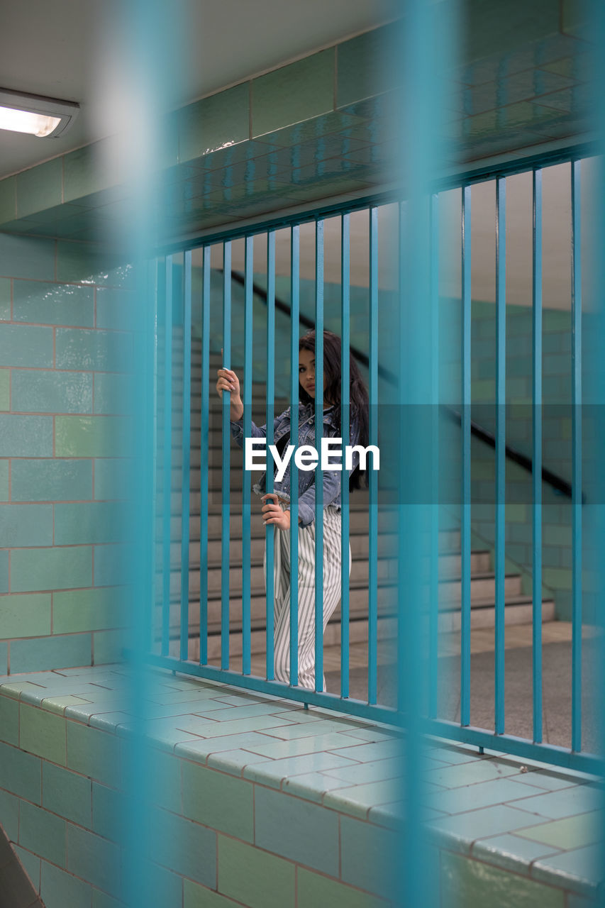 WOMAN STANDING BY WALL IN CORRIDOR