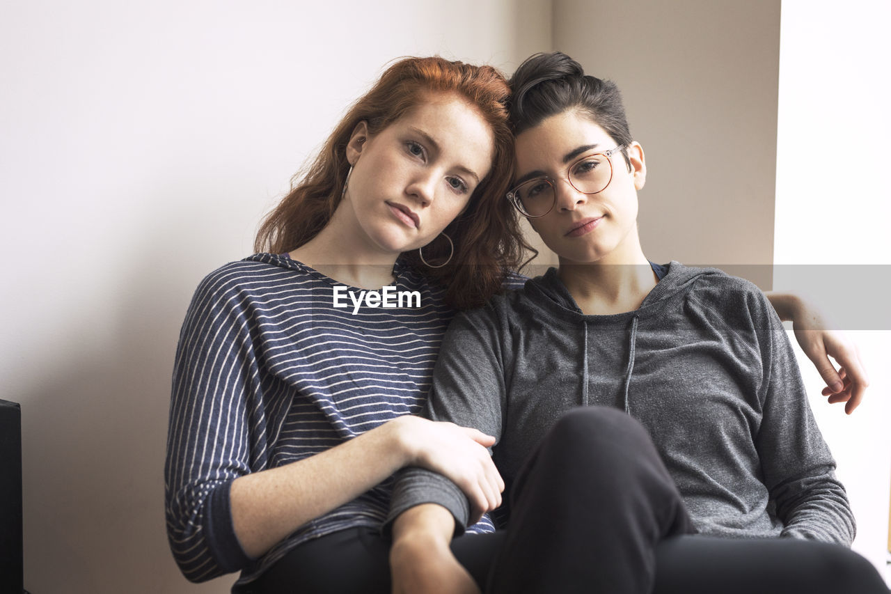 Portrait of lesbian couple sitting on chair at home