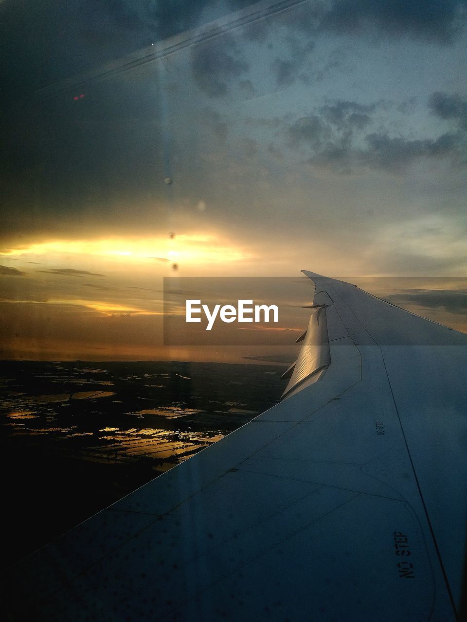 AERIAL VIEW OF SEA AND AIRPLANE WING DURING SUNSET