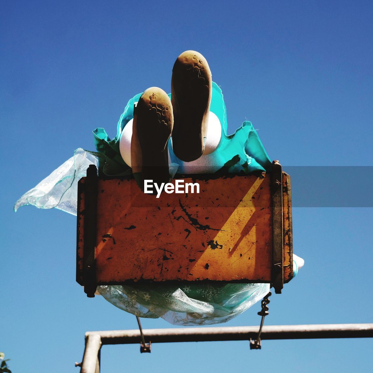 Low angle view of woman swinging against clear blue sky