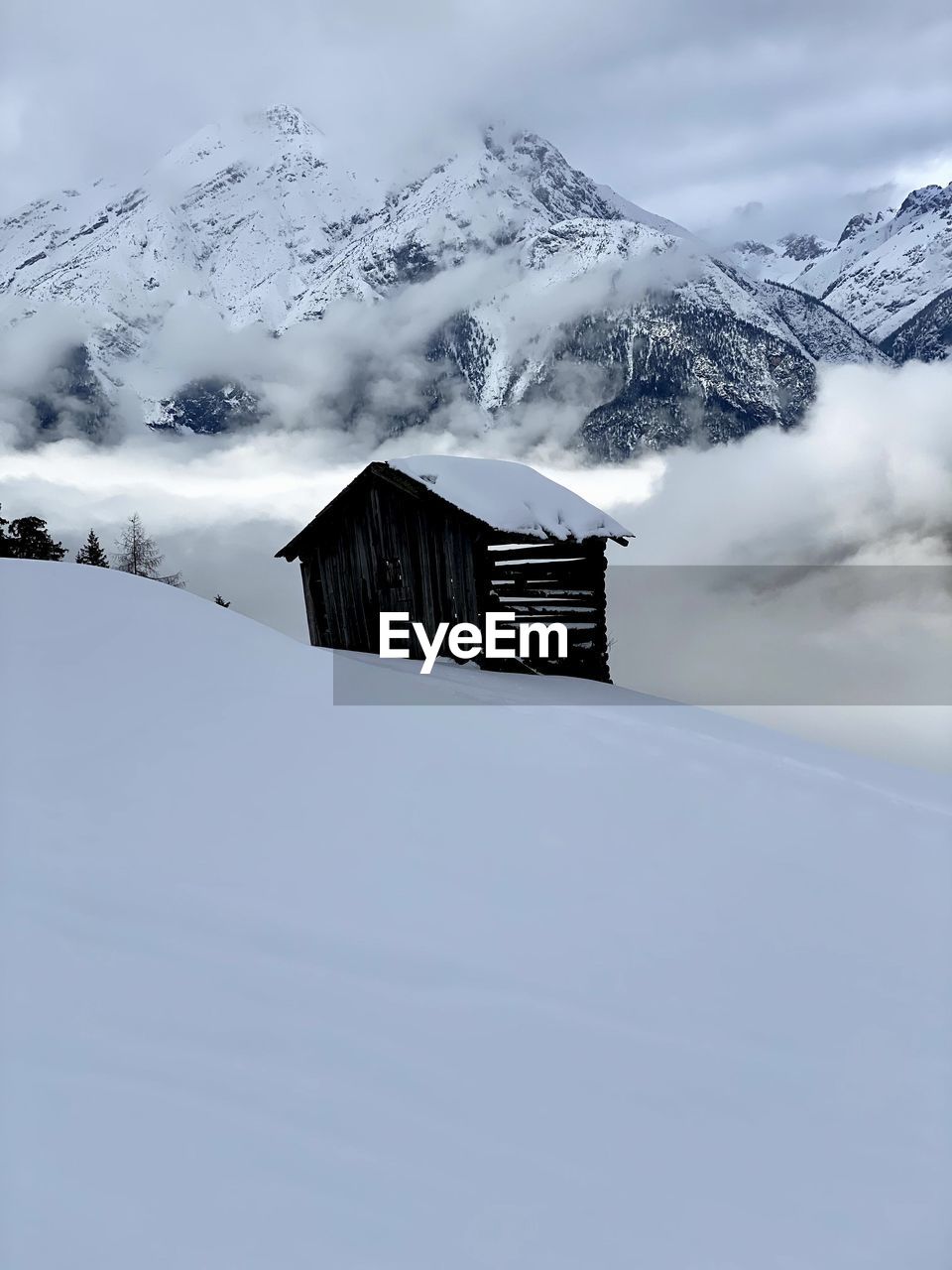 Barn on snow covered mountain against sky