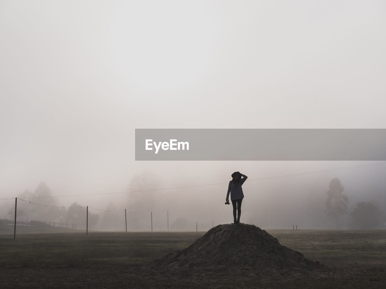 Silhouette woman standing on heap in foggy weather