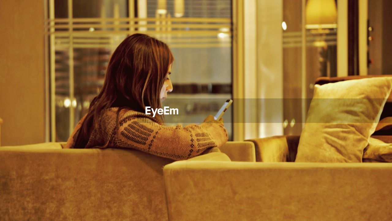 SIDE VIEW OF WOMAN USING PHONE WHILE SITTING IN BUS