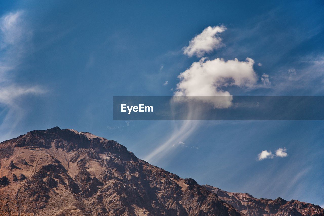 Low angle view of mountain and clouds against sky