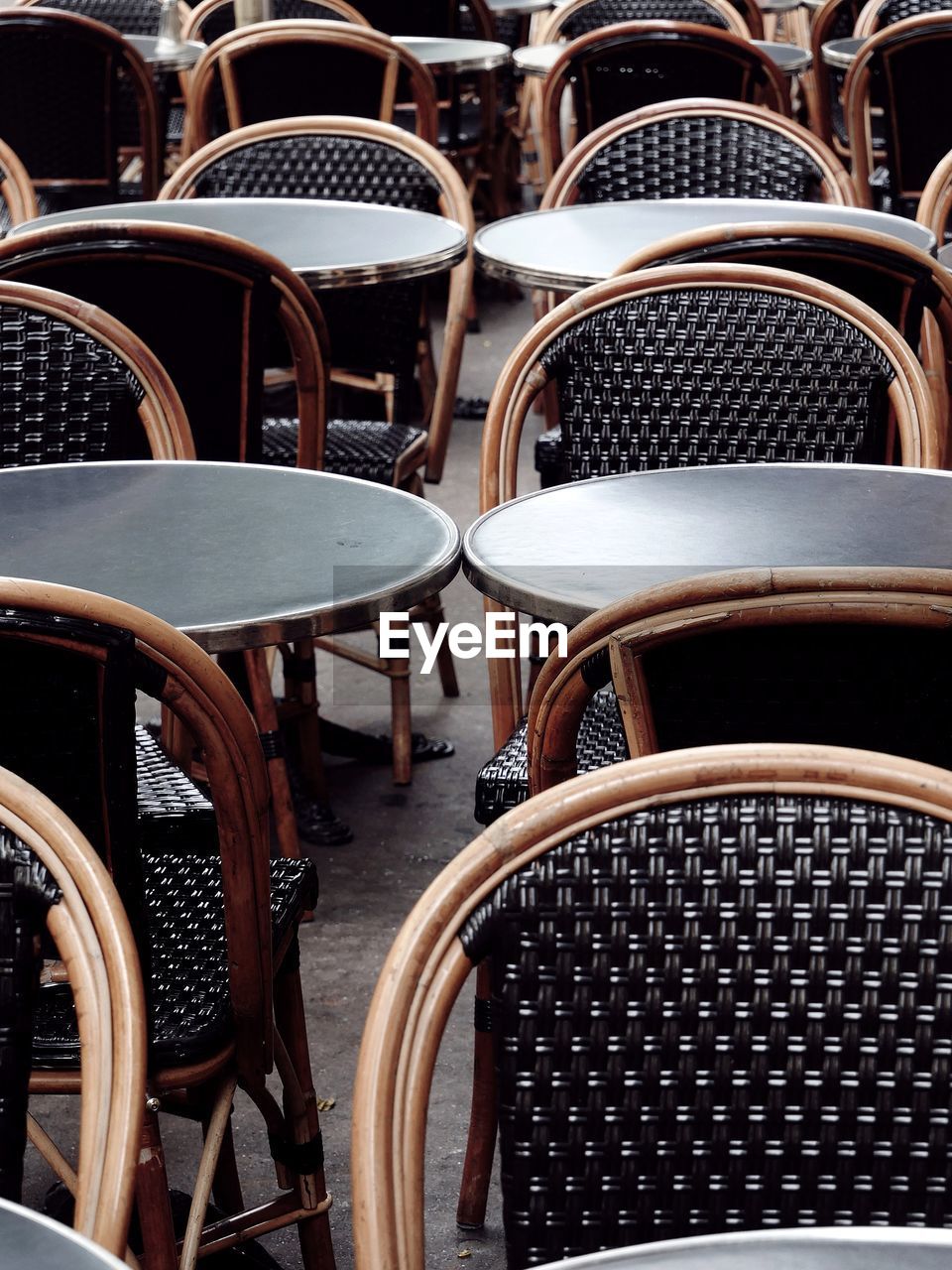 Empty chairs and tables at sidewalk cafe