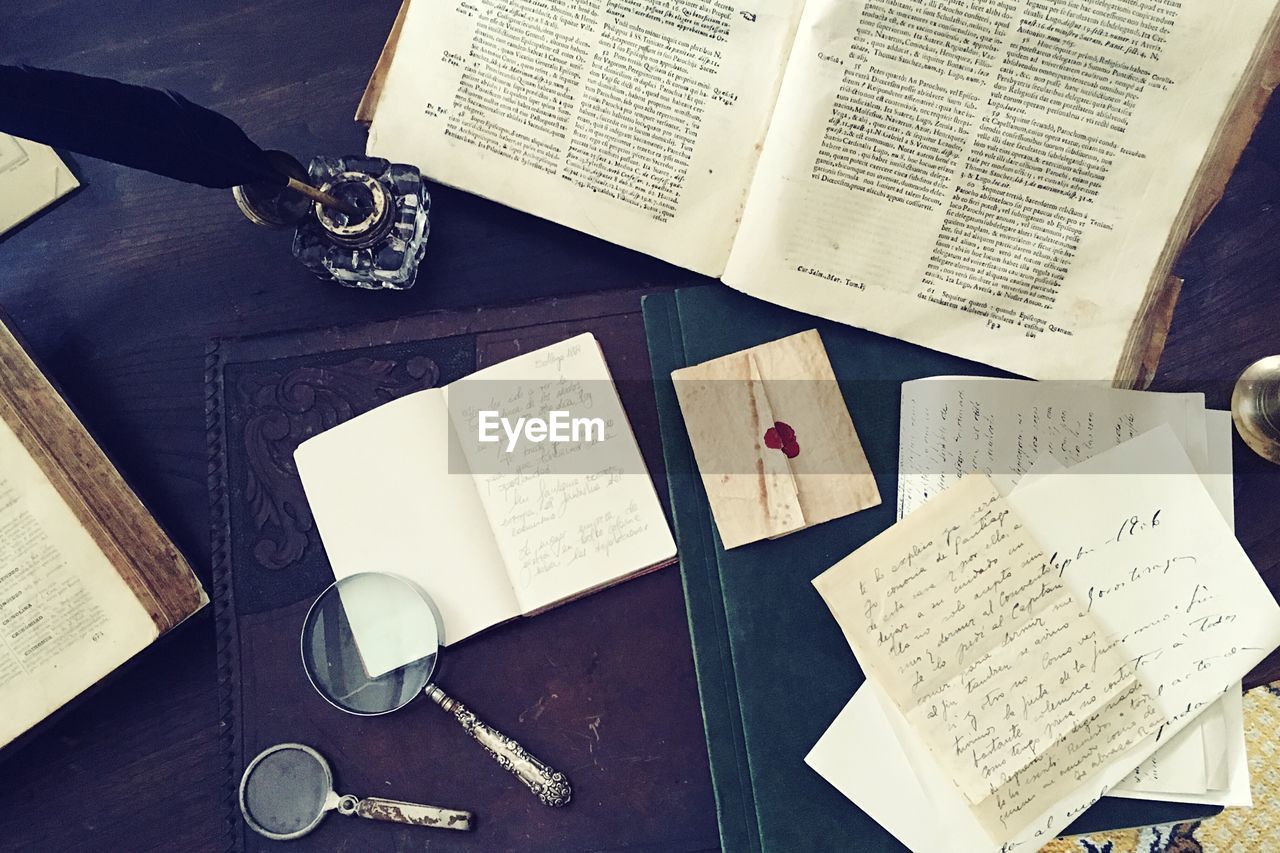 HIGH ANGLE VIEW OF OPEN BOOK ON TABLE AT HOME