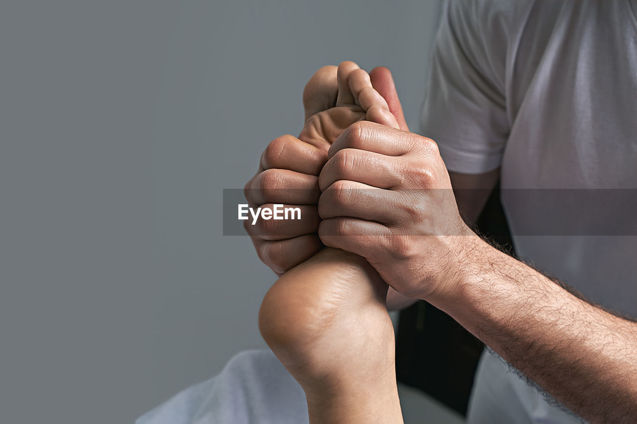 hand, adult, arm, men, studio shot, finger, limb, person, indoors, one person, gray background, human leg, human limb, emotion, gray, close-up, copy space, healthcare and medicine, holding, clothing, midsection, human face, pain