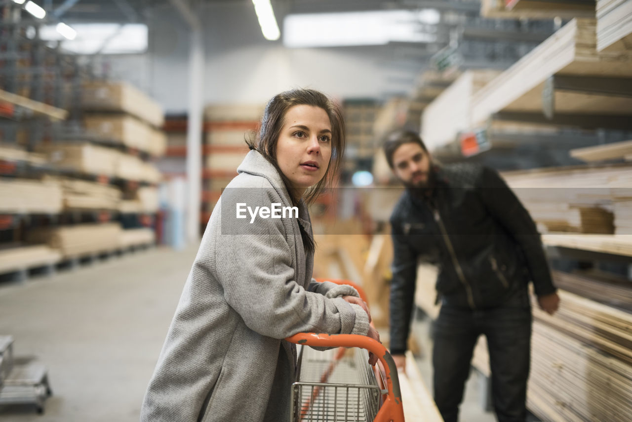 Couple looking away while standing in hardware store warehouse