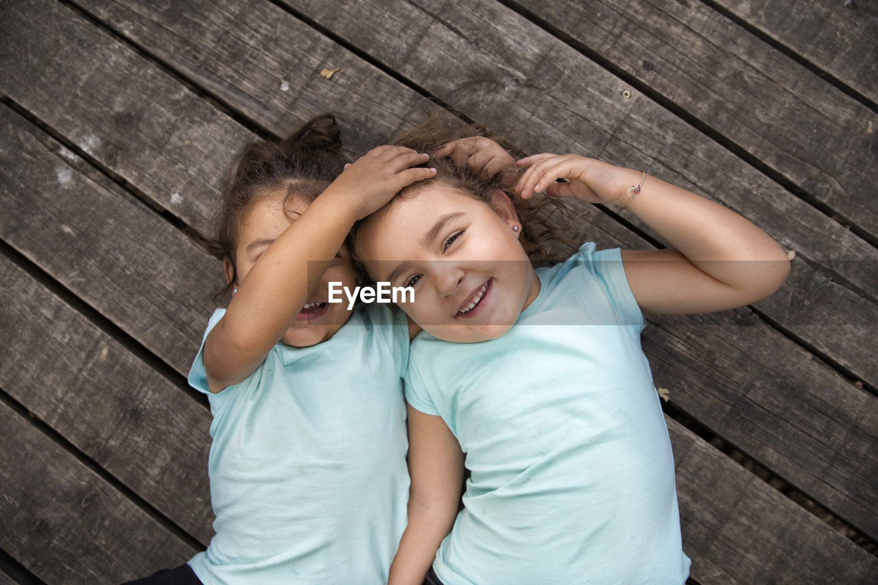 High angle portrait of cute sisters lying on deck