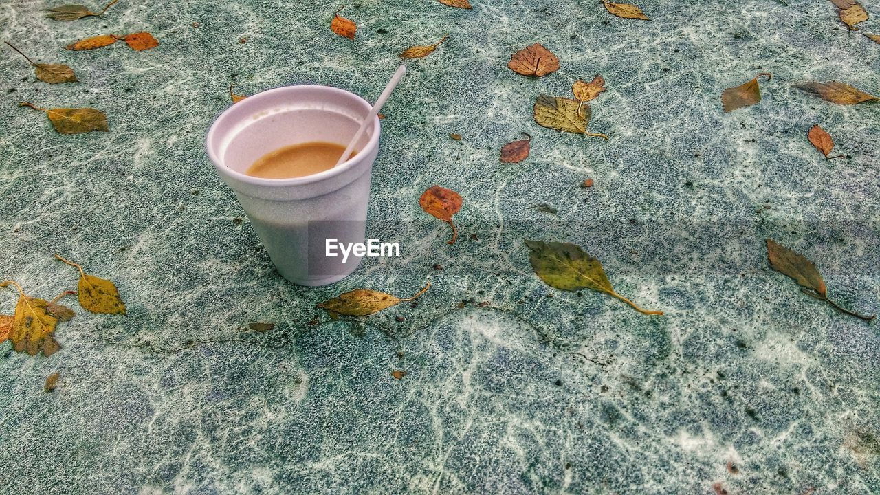 HIGH ANGLE VIEW OF COFFEE CUP ON GROUND