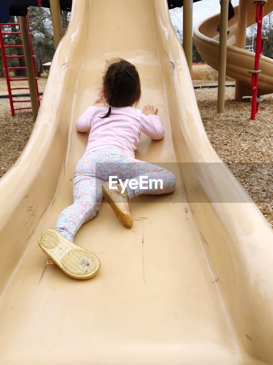 Rear view of girl on slide at playground