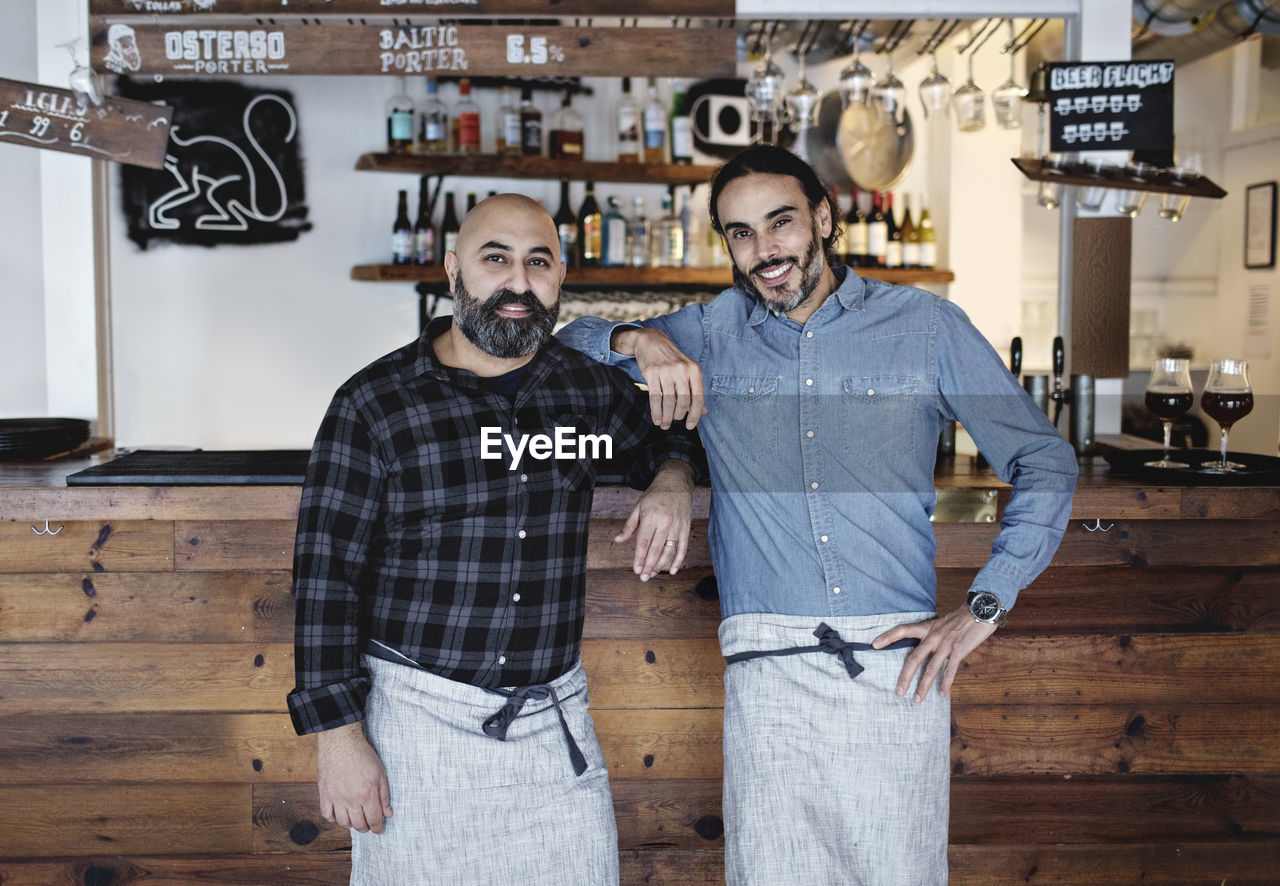 Portrait of male partners standing at bar counter