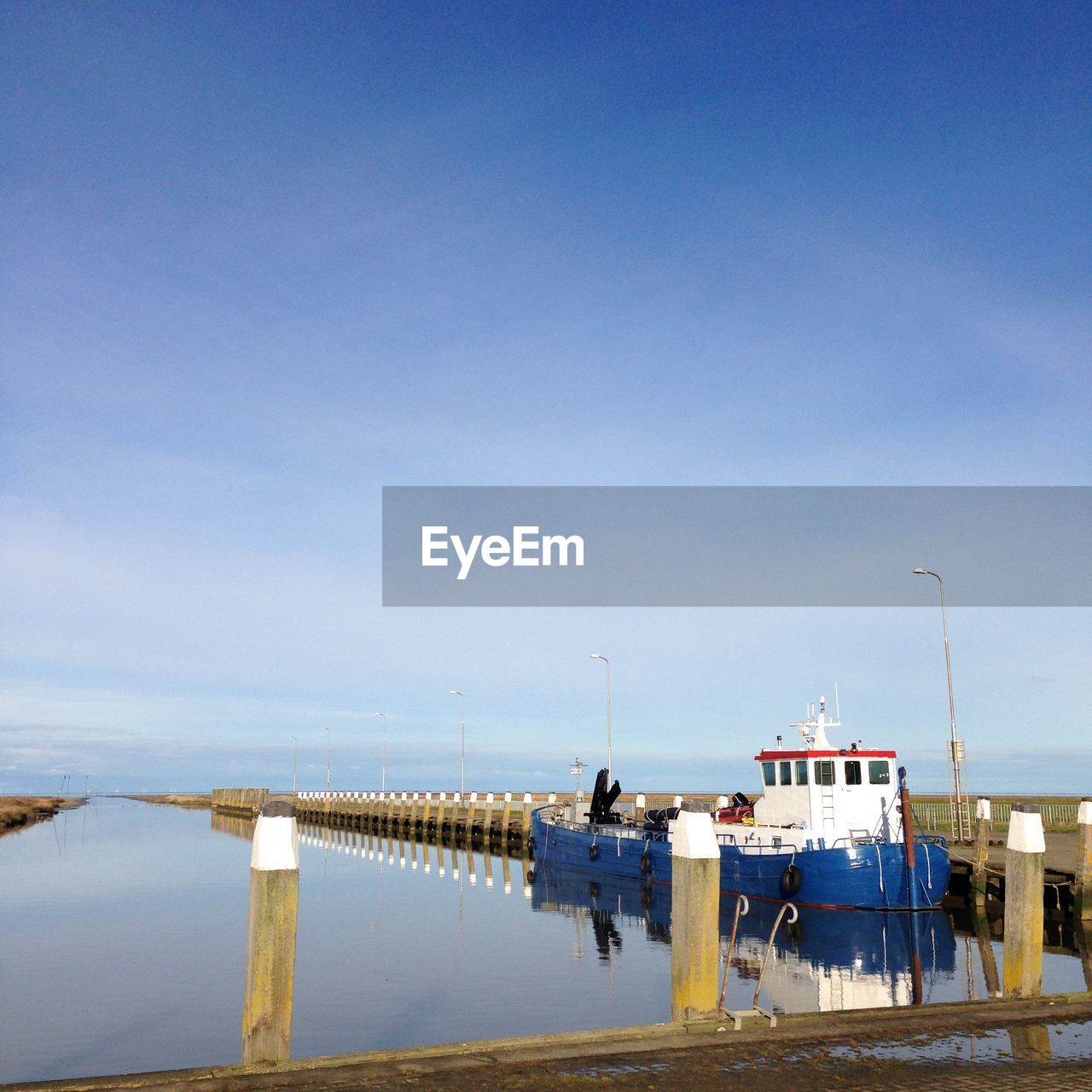 Fishing boat moored in canal at noordpolderzijl against sky