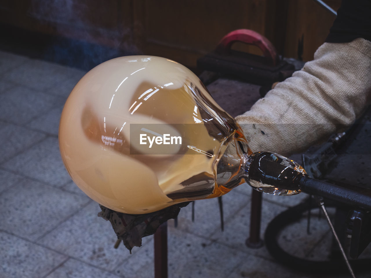 Man artists hands working on a blown glass piece. shaping glass bowl with wet tool. kunratice