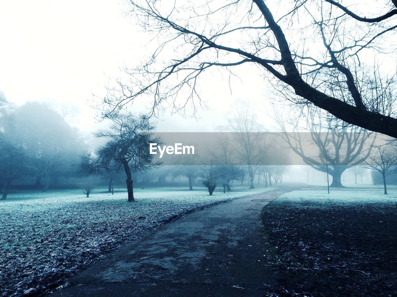 Empty road on field against sky during foggy weather