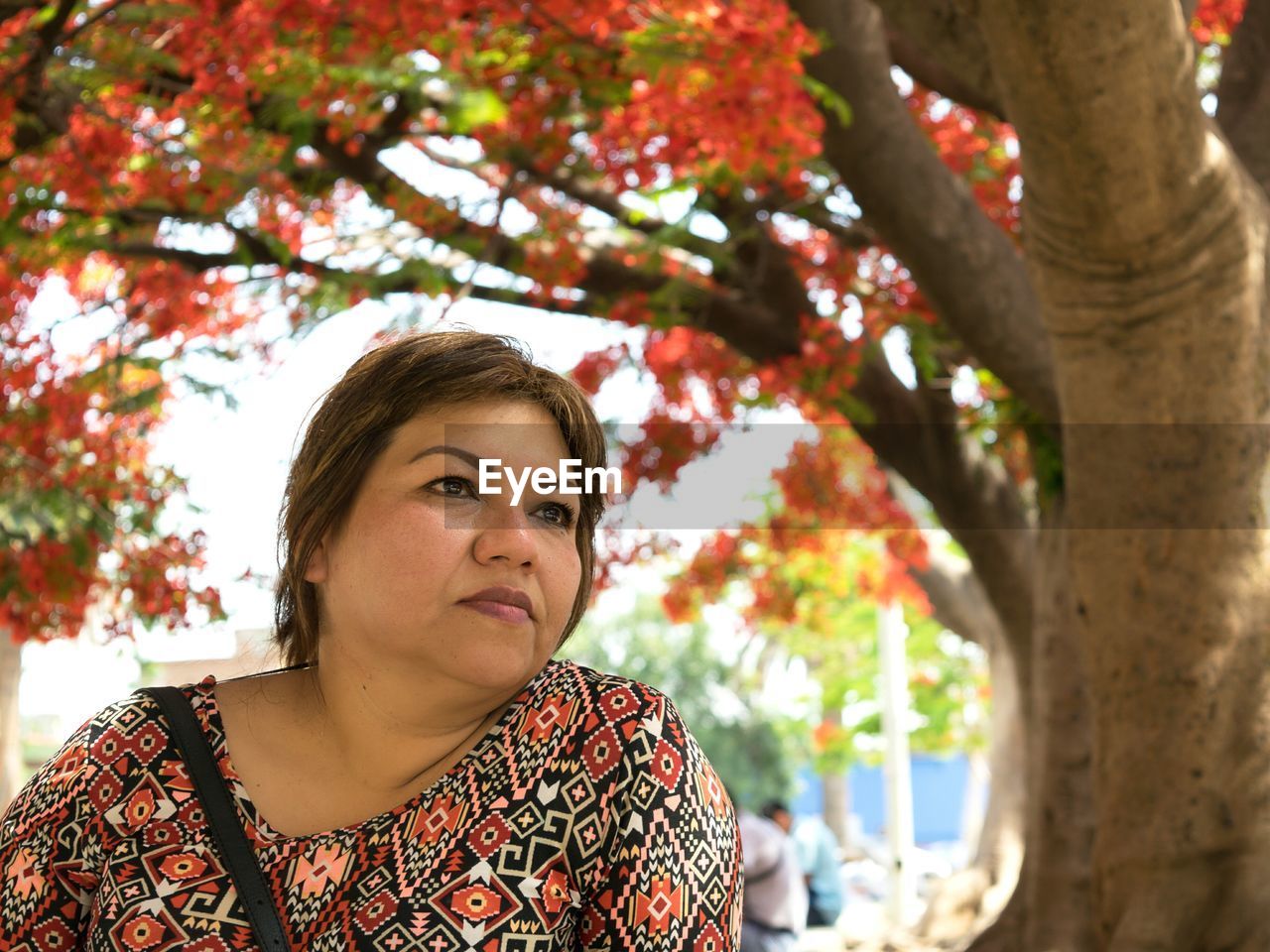 PORTRAIT OF YOUNG WOMAN STANDING BY TREE