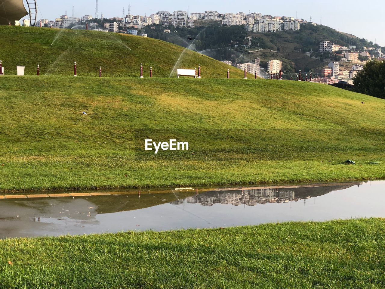 SCENIC VIEW OF FIELD BY LAKE AGAINST BUILDINGS