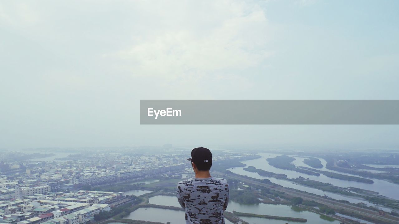 Rear view of woman standing on cityscape against sky