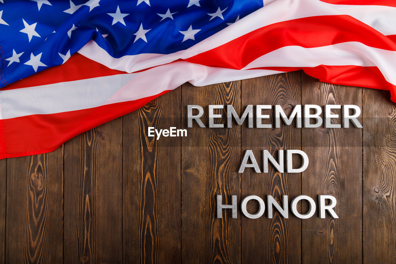 Words remember and honor laid with silver metal letters on wooden background with usa flag above