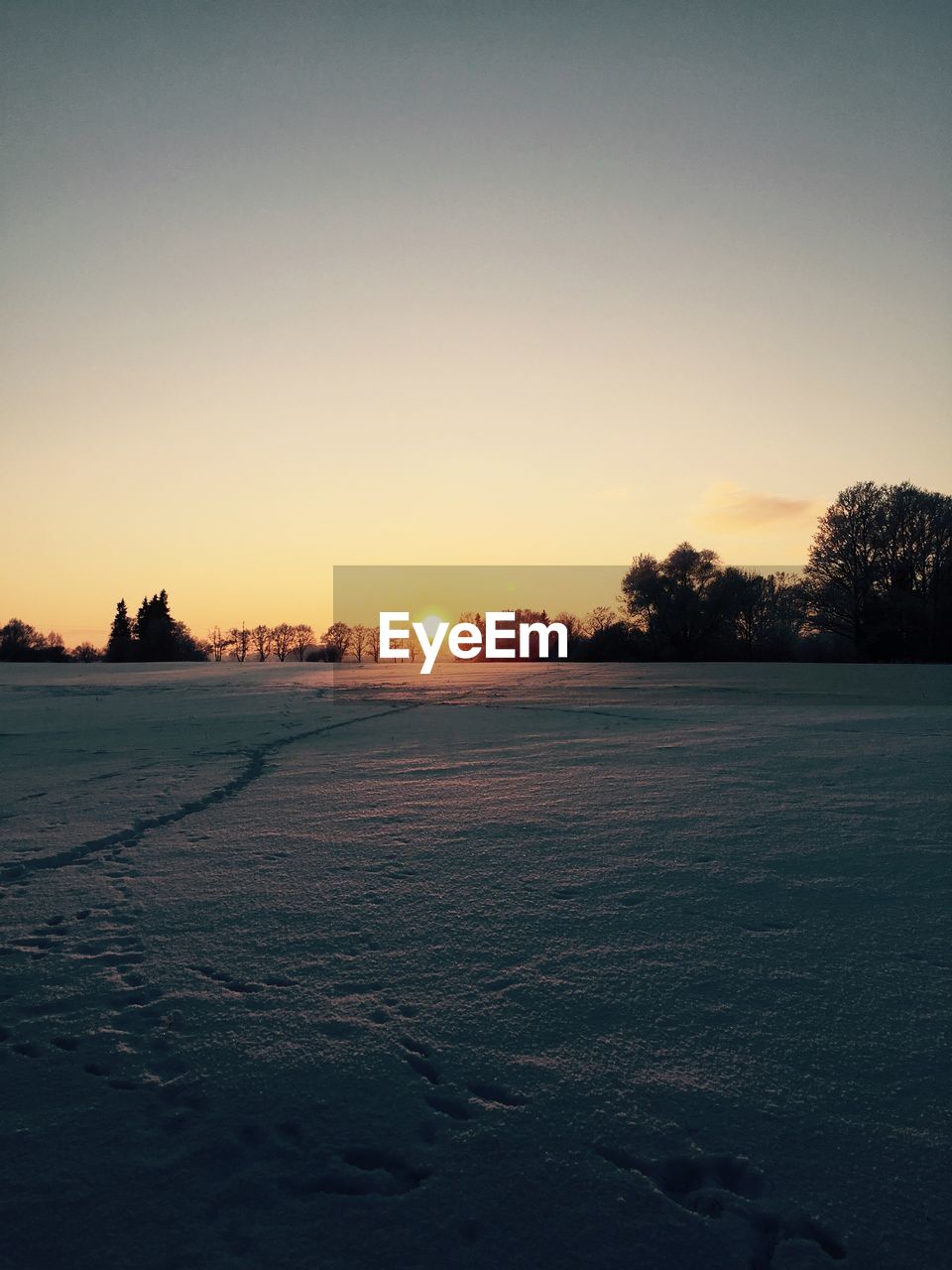 SNOW COVERED FIELD AGAINST CLEAR SKY DURING SUNSET