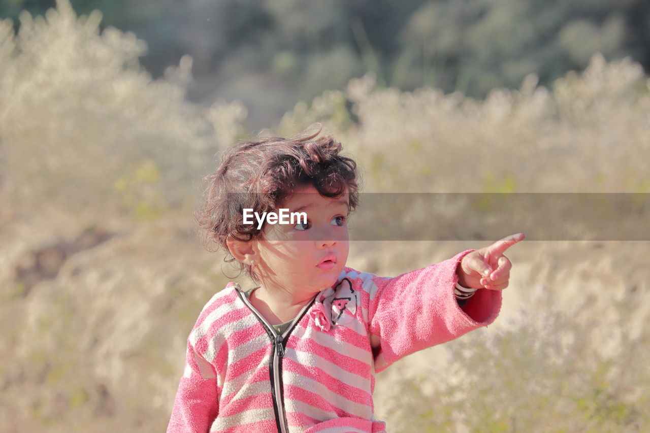 A small beautiful indian-origin child in the forest with a hand gesture telling something, india