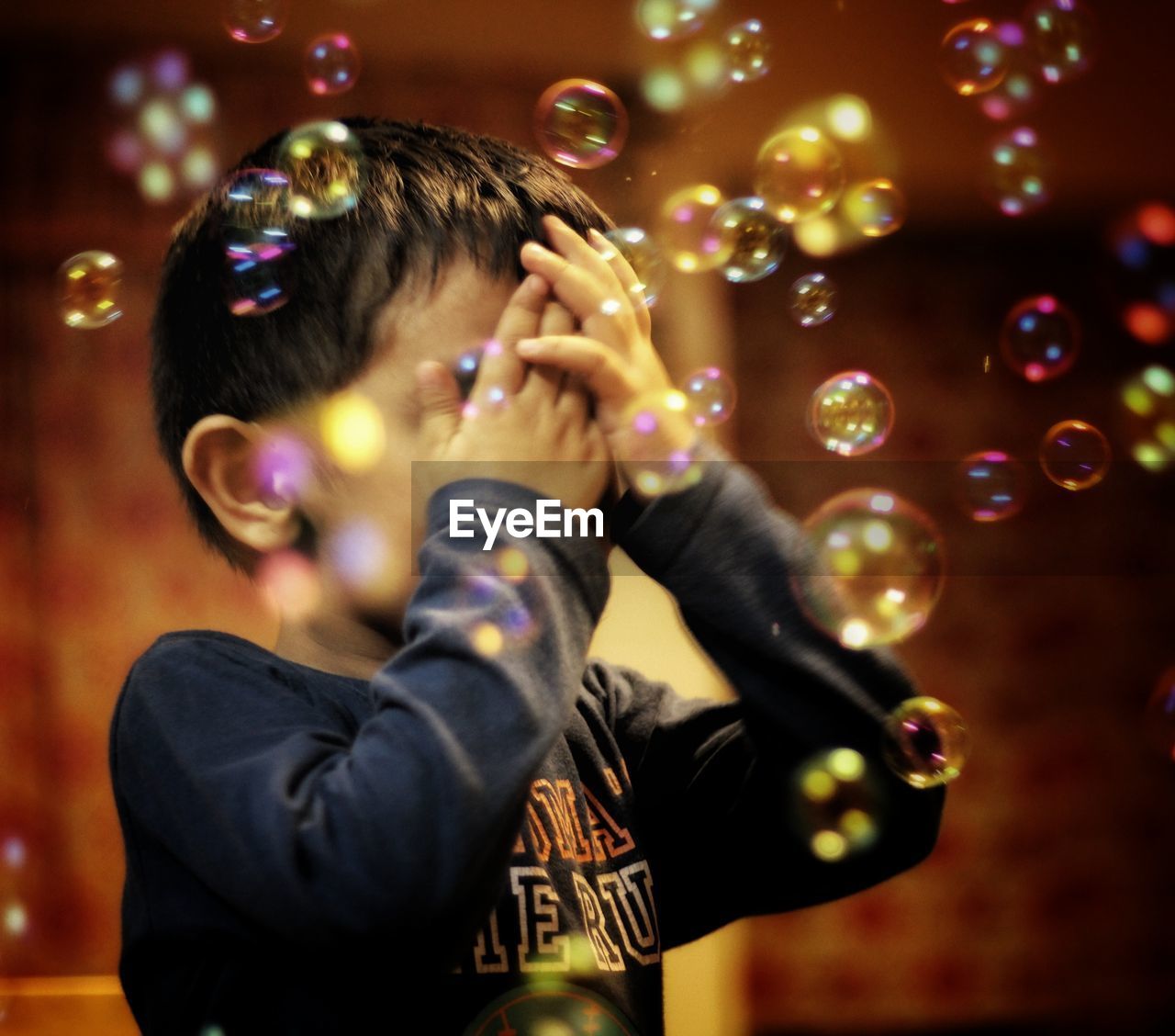Close-up of boy amidst bubbles in mid-air at night