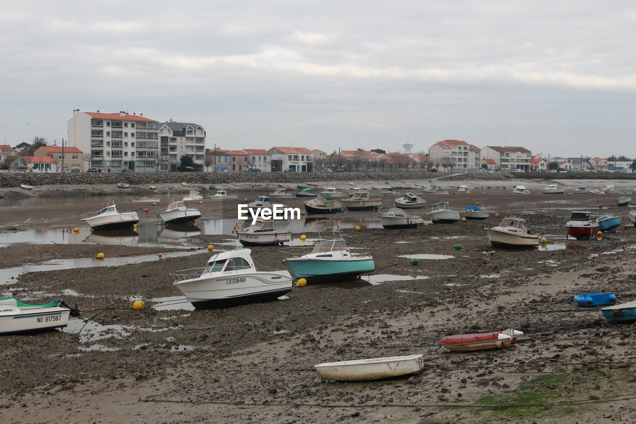 Boats moored at harbor against sky in city