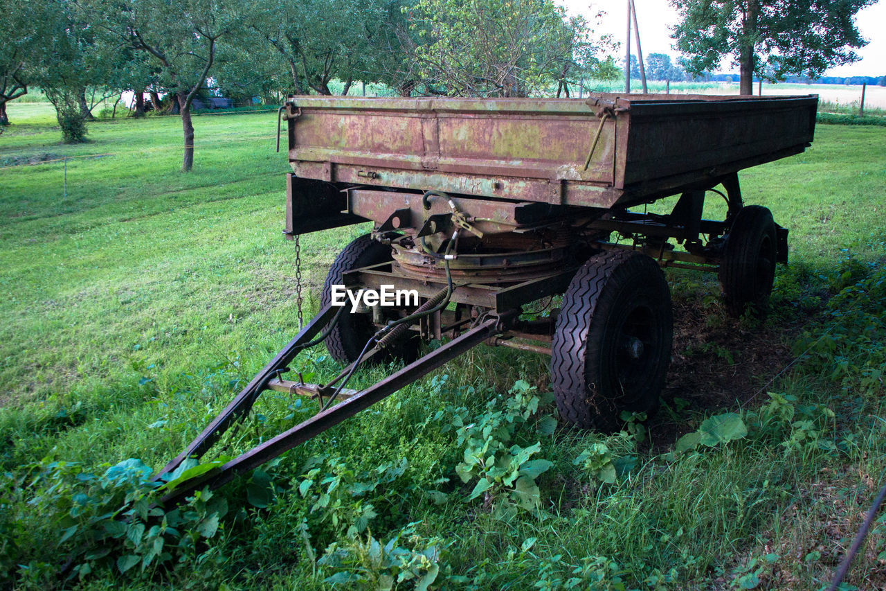 TRACTOR ON GRASSY FIELD AGAINST CLOUDY SKY