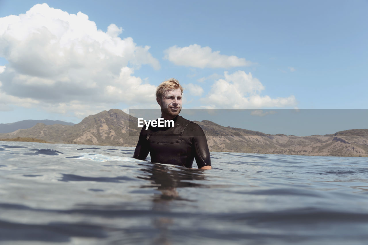 Portrait of happy man posing on surfboard in the sea