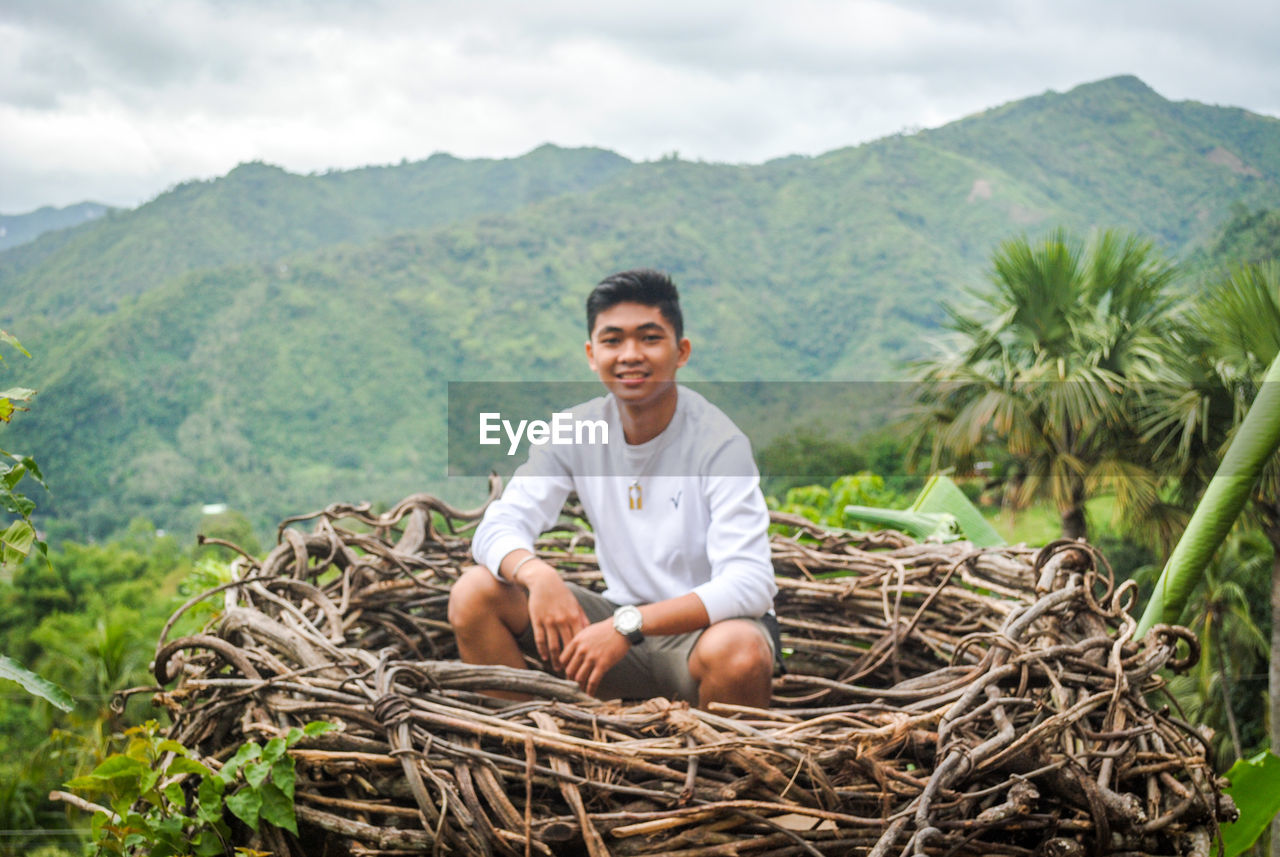 Portrait of smiling young man sitting on mountain nest