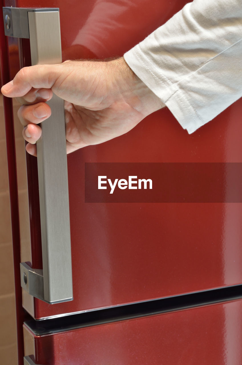 Hand on door handle of a red refrigerator