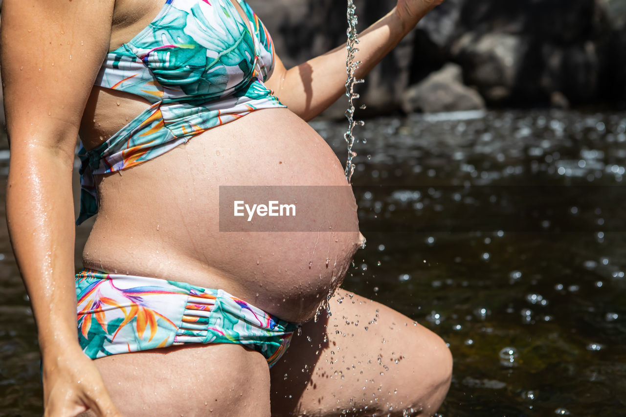 Midsection of pregnant woman in bikini