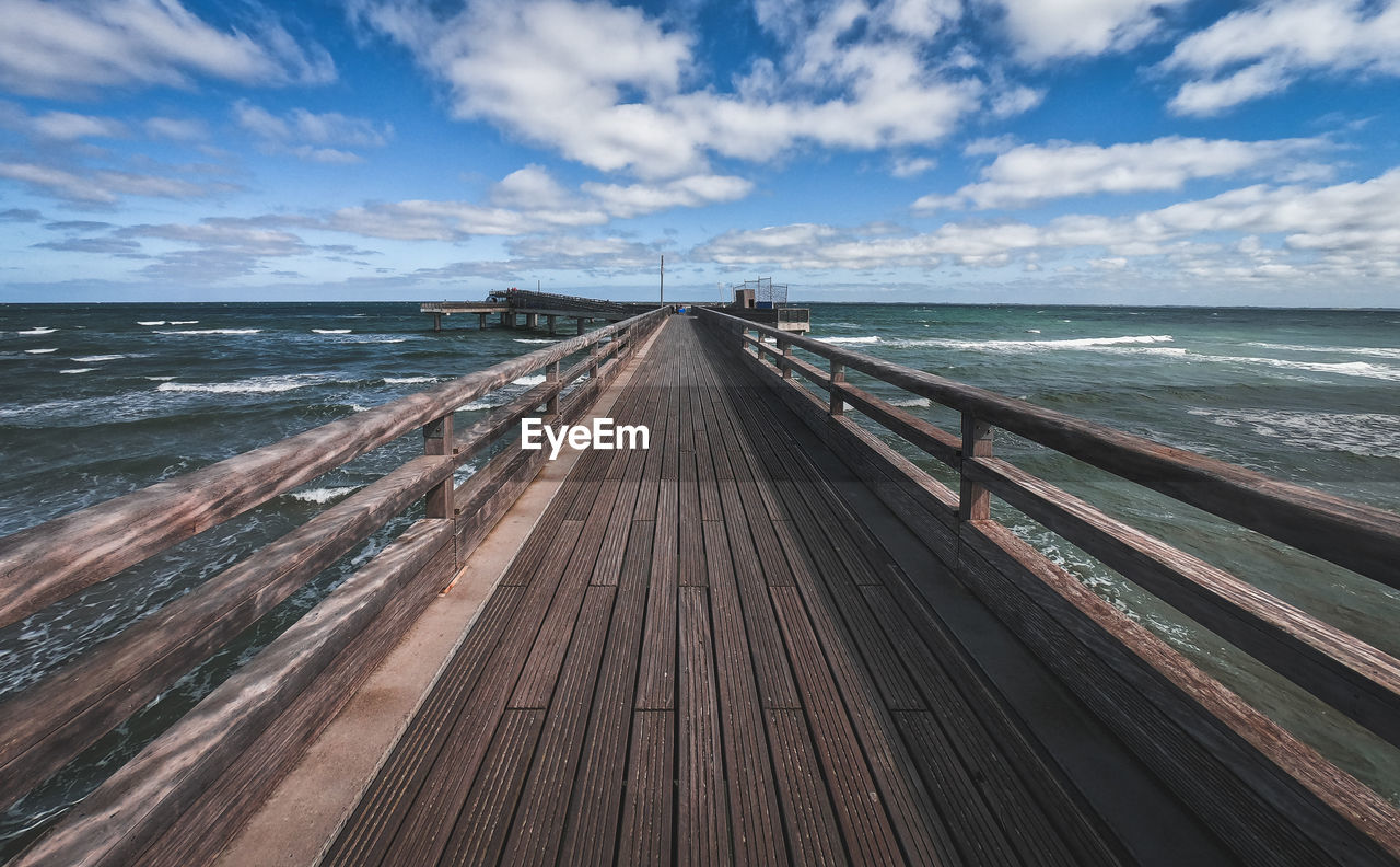 SURFACE LEVEL OF WOODEN PIER ON SEA AGAINST SKY
