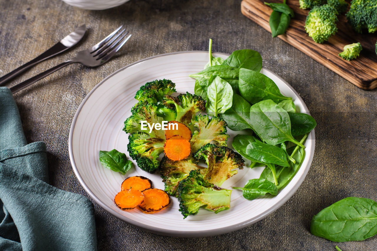 Grilled broccoli and carrots and fresh spinach leaves on a plate. vegetable diet.