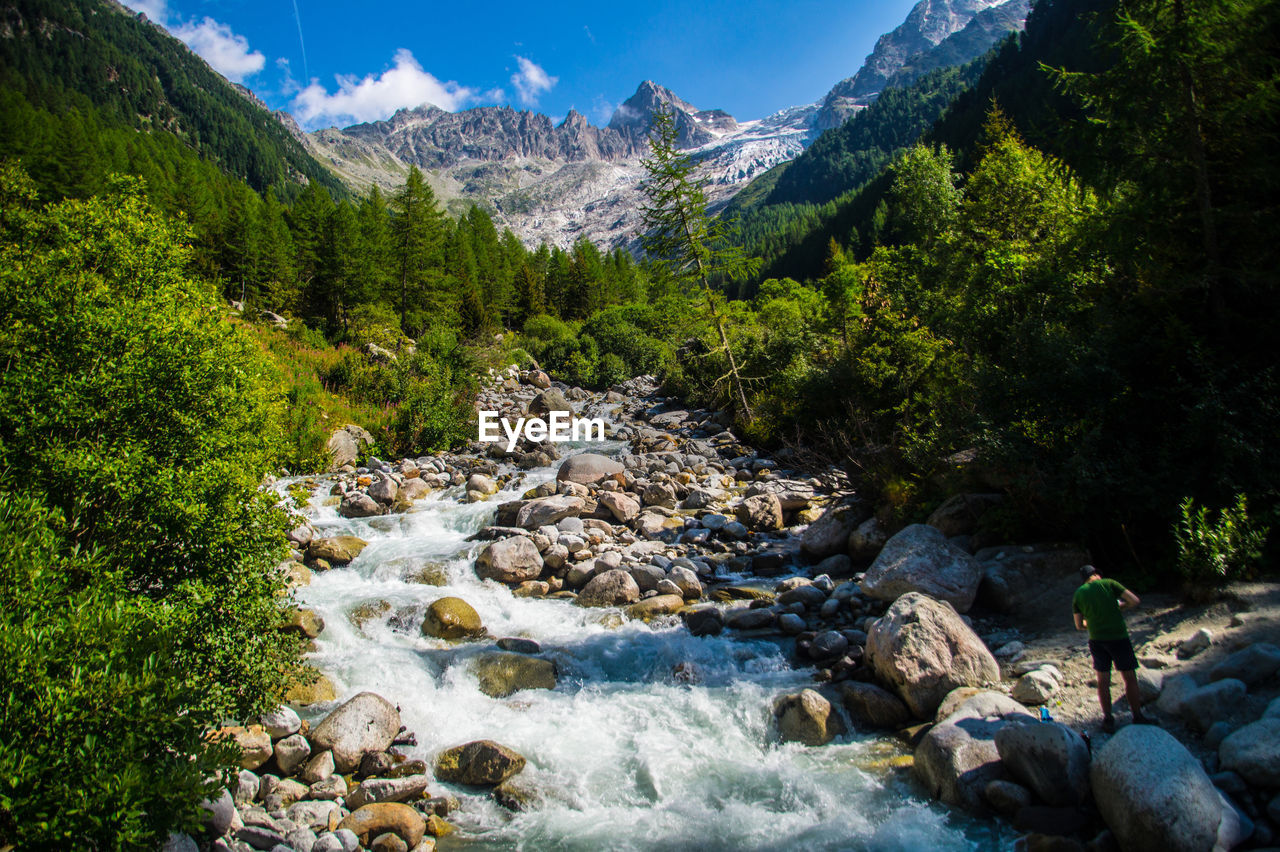 SCENIC VIEW OF STREAM FLOWING THROUGH ROCKS IN MOUNTAINS