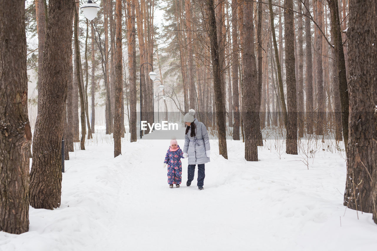 REAR VIEW OF PEOPLE ON SNOW COVERED LANDSCAPE